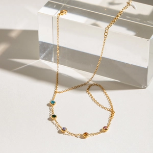 Detailed shot of gold plated bracelet with multicolored zircons on acrylic display