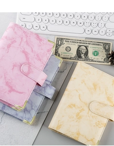 Detailed view of marble pattern A6 binders with gold metal corners and PU leather finish