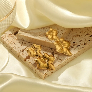 Détail de boucles d'oreilles feuilles dorées à double couche sur plateau de pierre