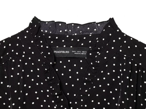 Detail of V-neckline with ruffled edges and black polka dot pattern on chiffon dress
