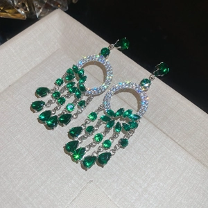 Vue détaillée de boucles d'oreilles en argent avec pierres vertes et franges de pompons