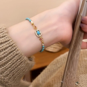 Detailed view of turquoise and pearl beaded bracelet with zircon inlay on a model's wrist