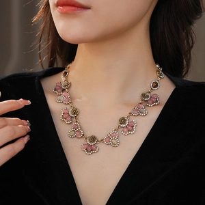 Close-up of vintage flower necklace with pink gems and tiger eye stones on model