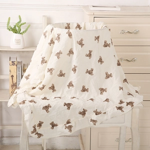Close-up of muslin cotton baby blanket featuring brown bear prints and crinkle texture
