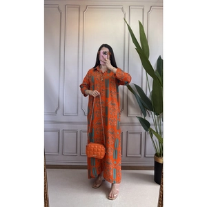 Dettaglio di un vestito lungo arancione a maniche lunghe con stampe geometriche blu