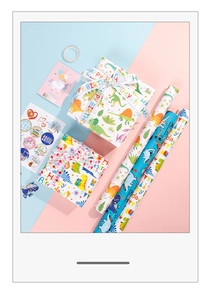 Flat lay of dinosaur and unicorn gift wrap set with birthday cards and ribbons