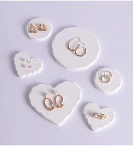 Close-up of gold earrings and pearl studs on heart-shaped display stands