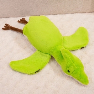 Detail of soft green pterosaur plush toy with smooth texture on white carpet