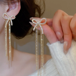 Macro shot of elegant golden bowknot tassel earrings with shimmering cubic zirconia