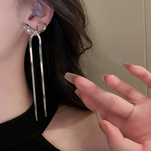 Close-up of long silver bow tassel earrings with snake chain on a model's ear