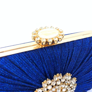 Macro shot of royal blue evening clutch with pleated fabric and rhinestone embellishments