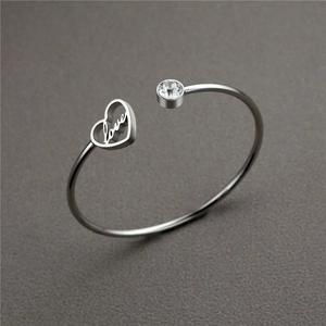 Detail of silver stainless steel open bangle with hollow heart love and round crystal
