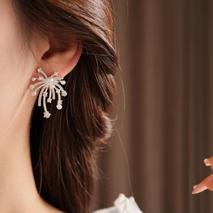 Macro detail of fireworks starburst earrings with pearls and crystals on ear