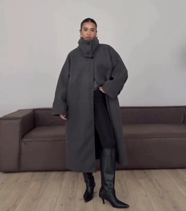 Detailed close-up of dark grey oversized long wool coat with buttoned stand collar