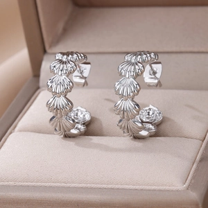 Detailed close-up of silver shell-inspired C-shape hoop earrings on a velvet jewelry box