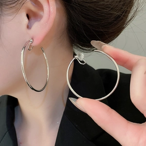 Close-up of a model wearing large silver round hoop earrings with a sleek polished finish