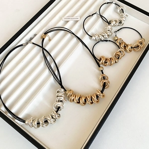 Detailed view of interlocked gold and silver metal rings with black leather cords on tray