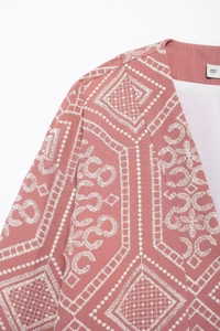Detailed view of pink kimono cardigan with white embroidery on shoulder and neckline