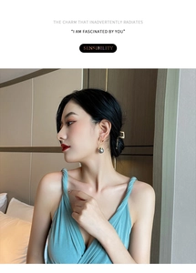 Close-up of elegant gold hoop earrings with dark grey pearl charms on female model
