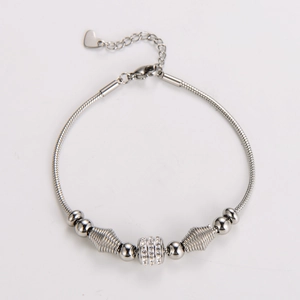 Detail of silver snake chain bracelet featuring sparkling charms and a heart pendant