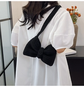 Détail d'un sac à bandoulière noir en maille en forme de nœud vu de l'arrière