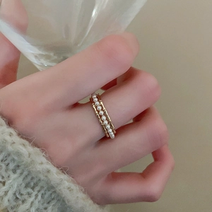 Close-up of elegant gold pearl ring on finger with soft aesthetic lighting