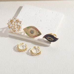 Evil eye and pearl rings set with zircon accents on a white textured background