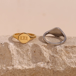 Detailed close-up of gold and silver signet rings with LTJ engraving on natural rock