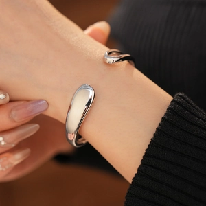 Close-up of a minimalist fluid teardrop bangle with a high-polished silver mirror finish