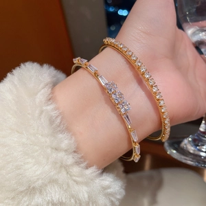 Detail of 18K gold plated open bracelets with sparkling zircon stones on model's wrist