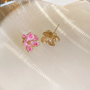 Macro shot of pink enamel flower earrings with gold base and needle backing design