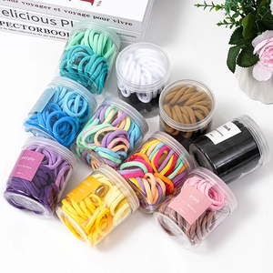 Candy colored elastic hair ties set in clear jars on a minimalist white background