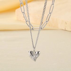 Gros plan d'un collier double épaisseur en acier inoxydable avec pendentif cœur argent
