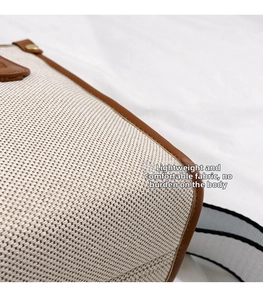 Close-up of canvas tote bag with brown leather trim and striped shoulder strap