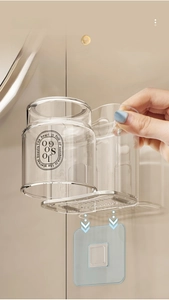 Detail view of the wall-mounted toothbrush holder with a clear cup and adhesive strip