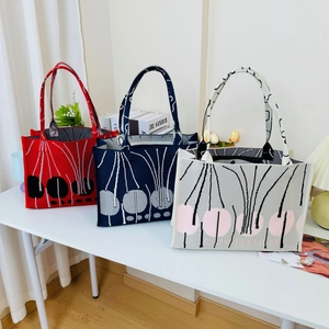Close-up of knit tote bags in red and blue featuring geometric floral patterns
