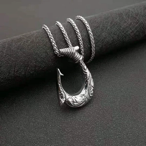 Close-up of a silver Viking fish hook pendant with intricate engravings on a textured scroll