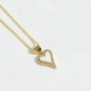 Detailed close-up of a gold heart pendant necklace with white enamel and sparkling zircons