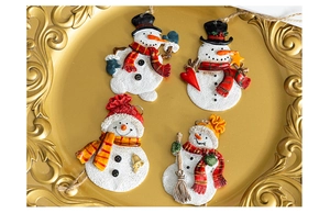 Detailed view of four resin snowman ornaments with festive red and gold accents in a tray