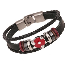 Macro detail of leather bracelet with wood beads and red anime Uchiha eye charm