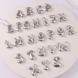 Silver 26 letters bubble pendant necklaces arranged on a white circular display tray