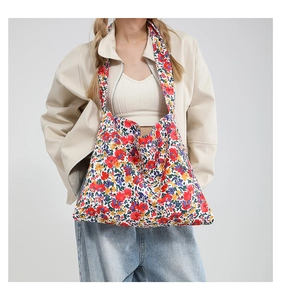 Borsa a tracolla in tela floreale capiente indossata da una modella con un outfit in stile casual