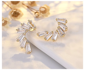 Macro detail of gold-plated crescent earrings with elegant rectangular cubic zirconia stones