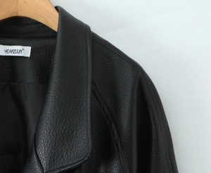 Close-up of black textured leather jacket featuring V-neck lapels and white brand label