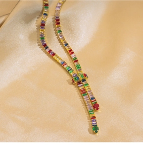 Detailed shot of gold-plated necklace with colorful rectangular gems on silk background