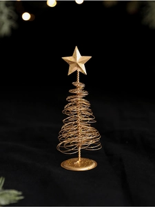 Close-up of golden spiral metal Christmas tree with star topper and festive bokeh