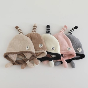 Macro detail of kids knitted earflap hats with penguin patch and soft yarn texture