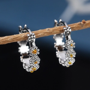 Macro shot of daisy hoop earrings featuring two-tone silver and gold floral details