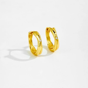 Detailed view of gold hoop earrings featuring a wavy textured design and a single diamond accent