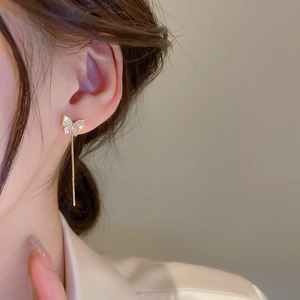 Close-up of elegant gold butterfly tassel earrings with sparkling white zircons on a model